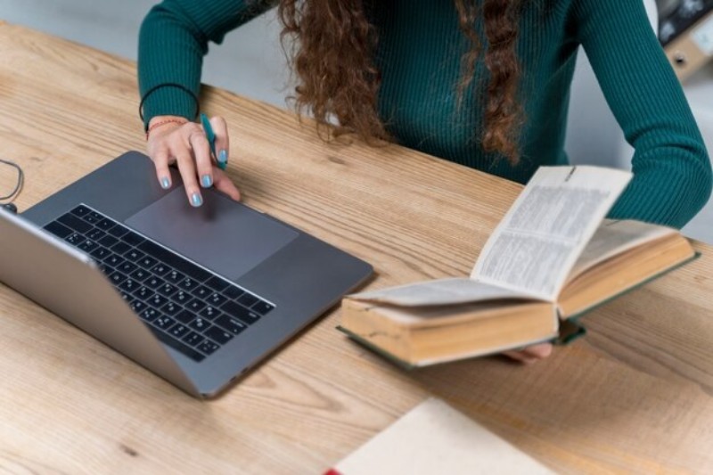 person using laptop and dictionary translating